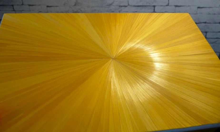 Dessus du couvercle d'une boite à bijoux décorée en marqueterie de paille jaune OR qui reflète la lumière en forme d'auréole