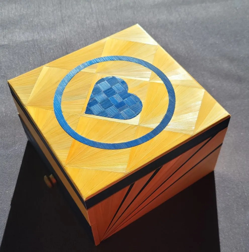 Boîte à bijoux en marqueterie de paille bleue et jaune avec des fleurs de diamants avec des reflets de lumière sur les fleurs